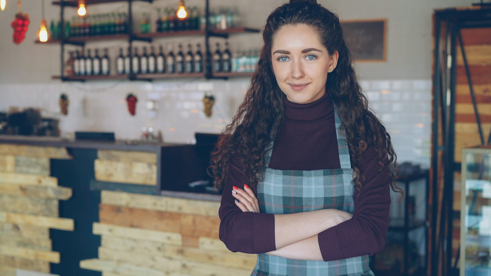 A café owner smiling behind the counter of her coffee shop